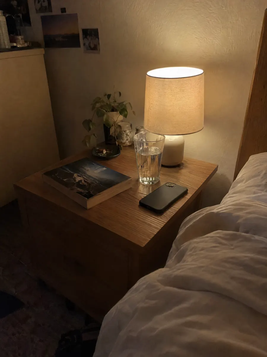A bedside lamp, a book and a glass of water at night